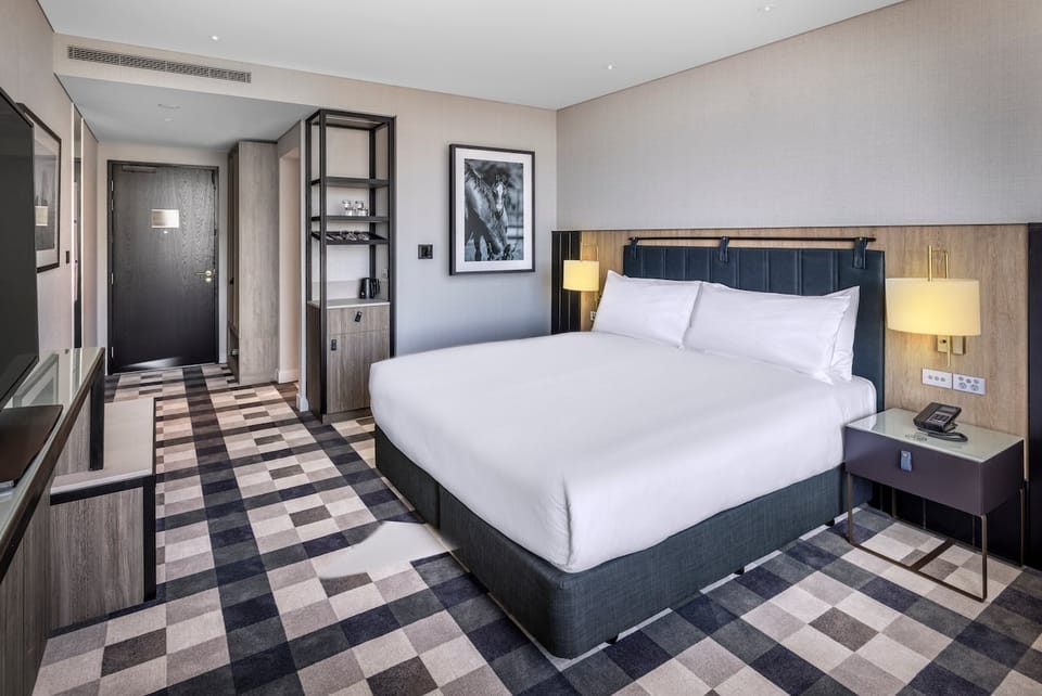 DoubleTree by Hilton Auckland Karaka – King Guestroom with navy padded headboard and checkerboard carpet